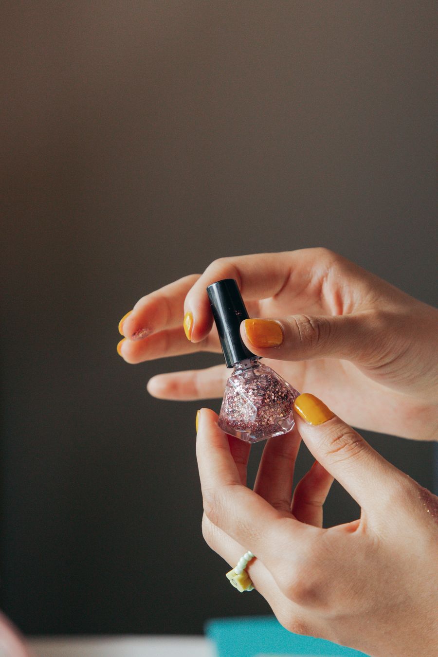 Mustard yellow nails with glitter polish bottle